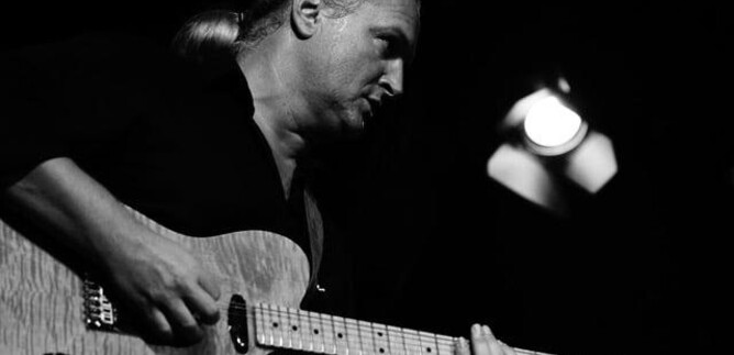 Ein Mann spielt Gitarre auf der Bühne. Die Atmosphäre ist intensiv und konzentriert. | © markus lackinger