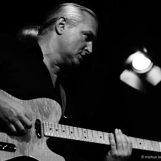Un homme joue de la guitare sur scène. L'atmosphère est intense et concentrée. | © markus lackinger